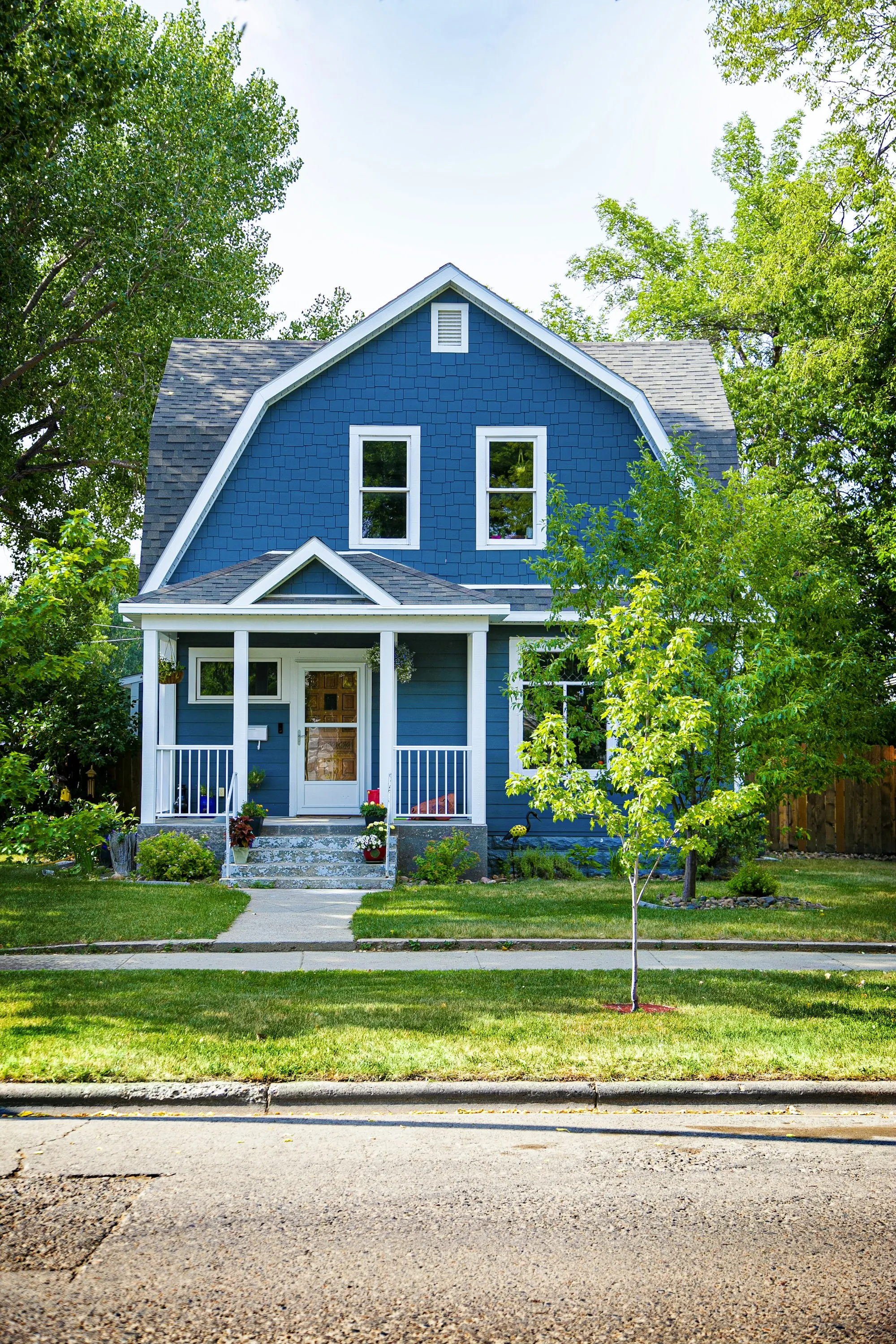 Blue house with a front porch and trees