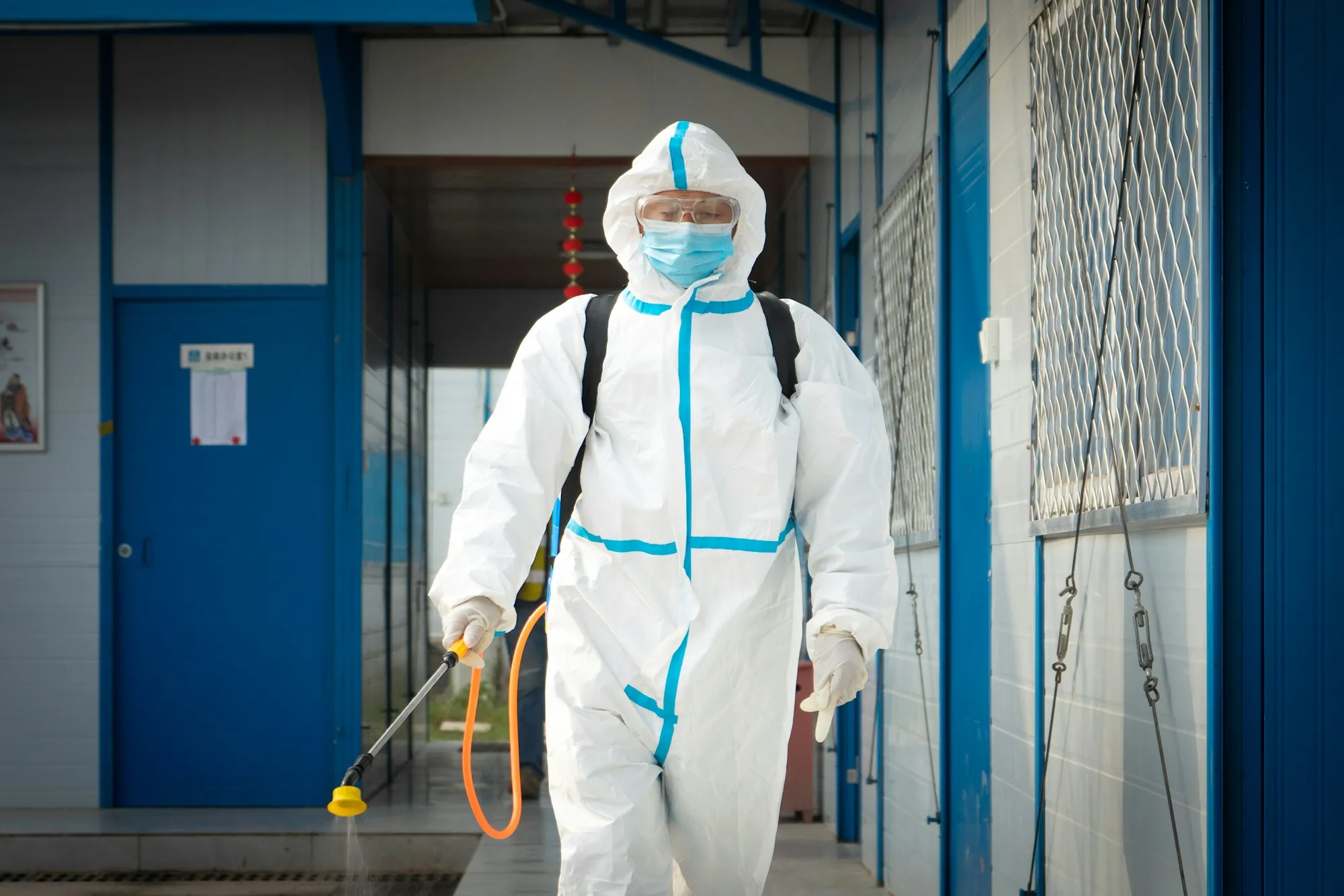 Worker in a protective suit spraying with a pump sprayer